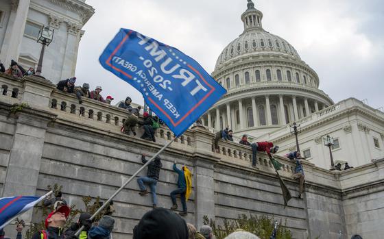 A man carrying a flag in support of Donald Trump joins with others during the riot at the Capitol.