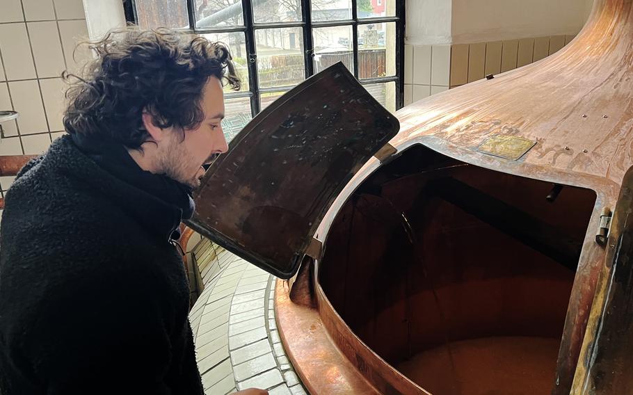 A man looks into a copper beer vat