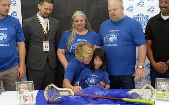 Kadena senior Tobin Kaiser signs a partial scholarship to play lacrosse at NCAA Division II Chowan University of Murfreesboro, N.D. He's surrounded by his parents Cara and Mike, Kadena High School principal Dr. James Bleecker, Tobin's brother Kyle and Island Youth Lacrosse Okinawa president John McClure. Seated on Tobin's lap is his 6-year-old niece Vivian.