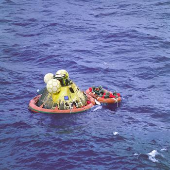 On July 24, 1969, the Apollo 11 crew await pickup by a helicopter from the USS Hornet, prime recovery ship for the historic lunar landing mission. The fourth man in the life raft is a United States Navy underwater demolition team swimmer.