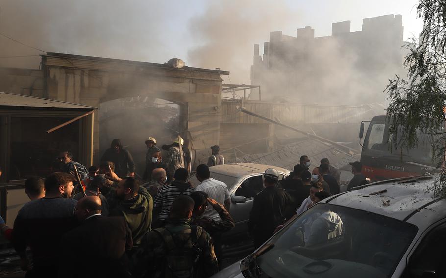 Security officers and rescuers gather at a destroyed building in Damascus on Thursday.