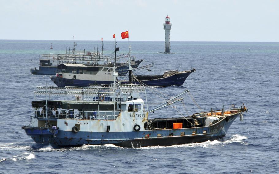 Chinese fishing vessels navigate past a beacon.