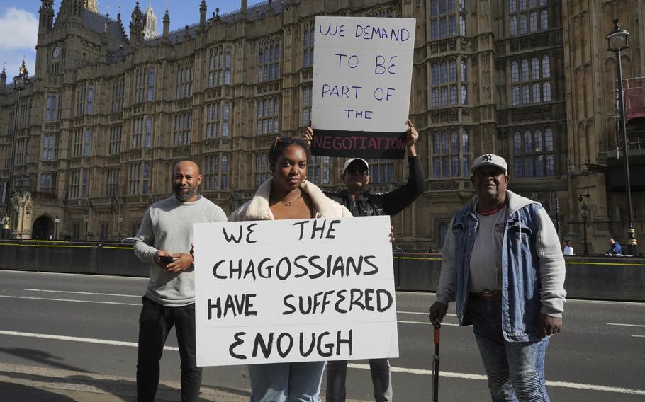 Chagossians hold up signs during a protest