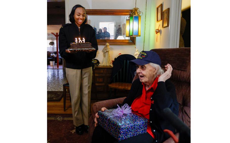 Navy ENS Raven Battles presents a birthday cake to Navy World War II veteran Elsie Kitty Rippin