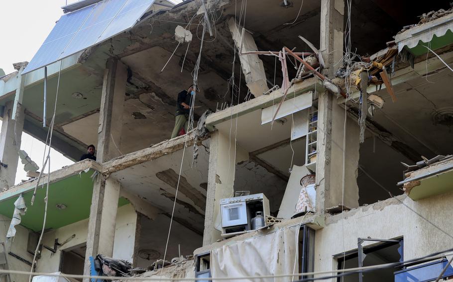 People inspect a destroyed building hit in an Israeli airstrike