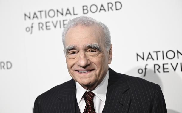 Martin Scorsese, in a pinstriped black suit jacket, white shirt and red diamond-patterned tie, smiles while posing for photos at the National Board of Review awards gala in New York on Jan. 11, 2024. 