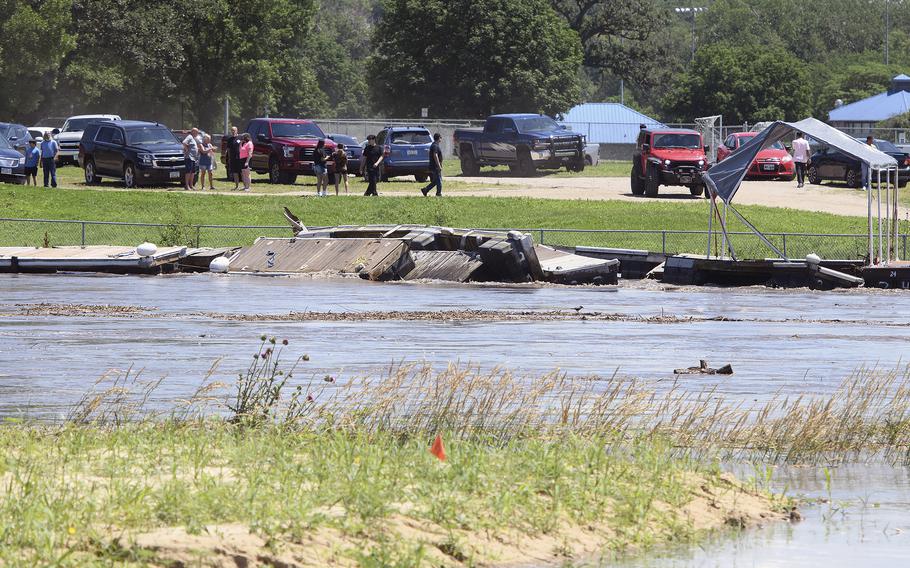 Onlookers watch as docks at the Missouri River Boat Club in Sioux City, Iowa, are battered by Big Sioux River floodwaters Sunday, June 23, 2024.