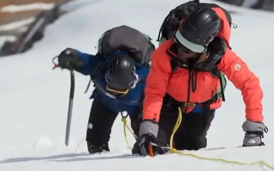 Ladeania Jackson and another contestant climb a snowy mountain,