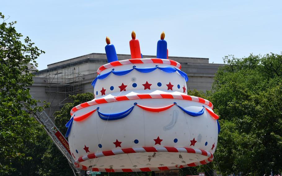 A giant inflatable birthday cake in patriotic colors fly high above the crowd at the Washington, D.C. Independence Day Parade on July 4, 2024.