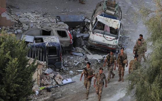 Lebanese army soldiers walk by destroyed cars at the site where an Israeli airstrike hit a building, in Barja village, south of Beirut, Lebanon, Saturday, Oct. 12, 2024. (AP Photo/Mohammed Zaatari)