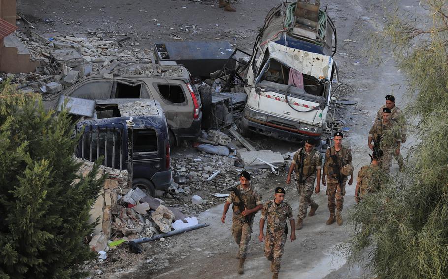 Lebanese army soldiers walk by destroyed cars at the site where an Israeli airstrike hit a building, in Barja village, south of Beirut, Lebanon, Saturday.