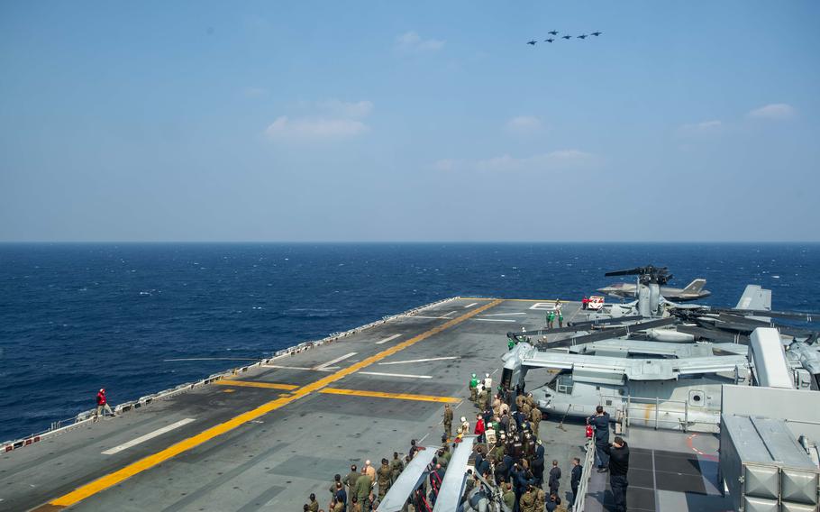 F-35 aircraft fly in the distance above the USS America.