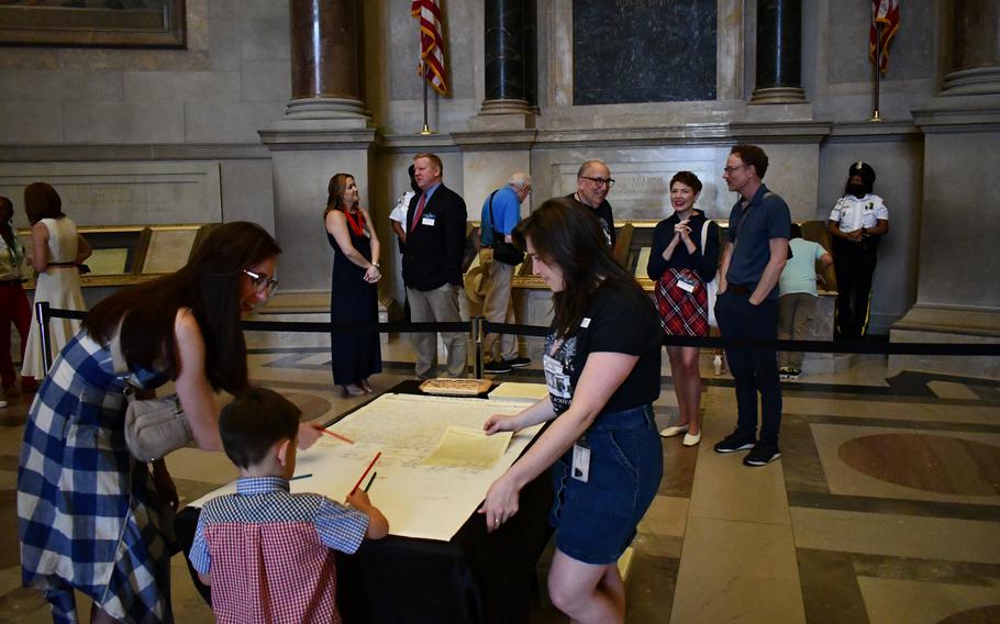 A young boy signs a replica of the Declaration of Independence inside the National Archives on July 4, 2024.