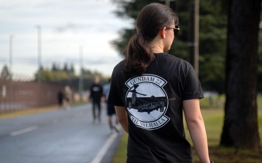 A participant walks along a paved road next to a patch of grass during a 5K race.