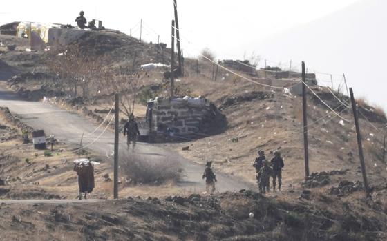 Israeli soldiers are seen from a distance on a hill.