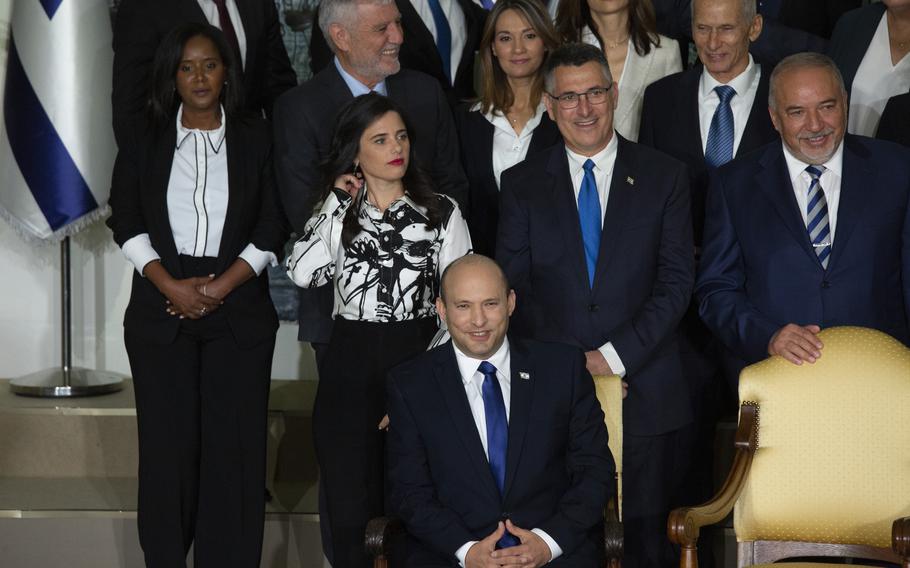 Israeli Prime Minister Naftali Bennett, seated, smiles as he waits to pose for a group photo with the ministers of the new government at the President's residence in Jerusalem on Monday, June 14, 2021.