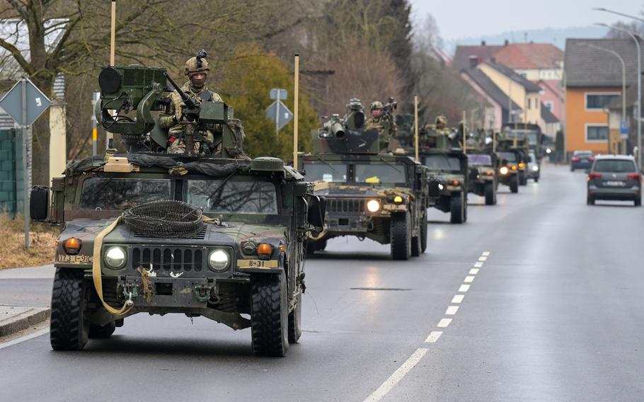 A convoy of U.S. military vehicles driven by Army paratroopers travels along a street in Germany.