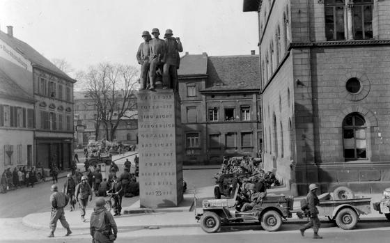 In a photo taken by a  Pfc. Warner of the 166th Signal Photo Co., a U.S. Third Army soldier guards German prisoners in the public square in Kaiserslautern, Germany, as other soldiers mill about, March 21, 1945. The Army seized the southwest German city from the Nazis a day earlier. Today people would recognize the  23rd Monument at center and the Fruchthalle at right.,

 


