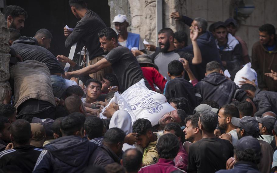 Palestinians gather around an aid vehicle distributing bags of flour.