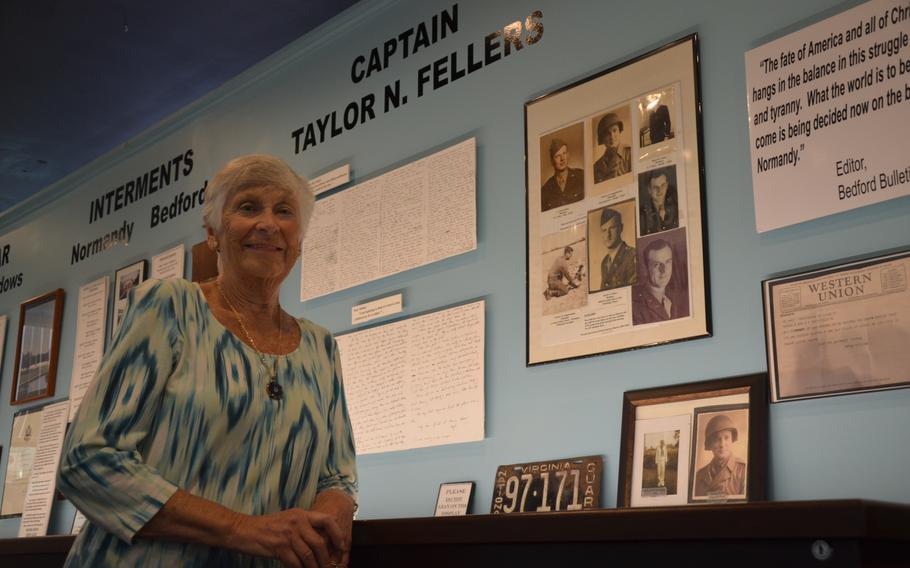 Liz Beverly standing in front of her uncle Capt. Taylor Fellers’ collection at the Bedford Boys Tribute Center on May 10, 2024. Fellers died on June 6, 1944, four days shy of his 30th birthday. He was one of 20 soldiers from Company A of the 116th Infantry Regiment, 29th Division that died on or shortly after D-Day 80 years ago.