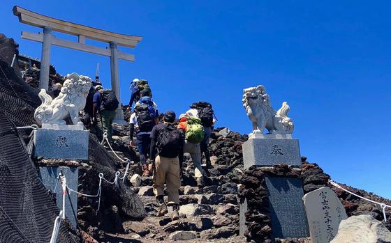 Hikers on the Yoshida Trail approach the torii that signals they've reached the summit of Mount Fuji, Japan, in August 2019.