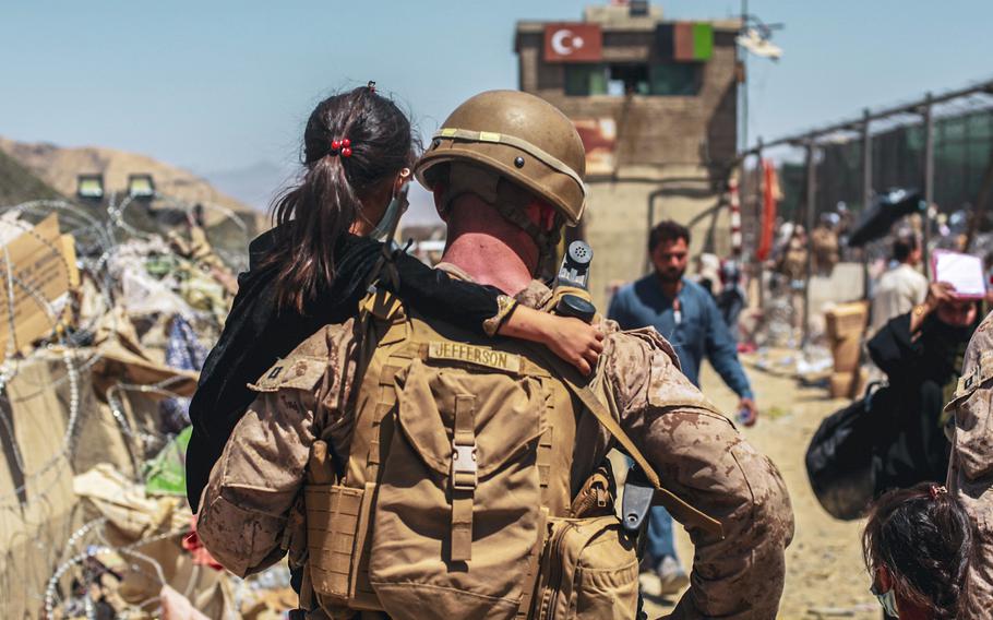 A Marine assigned to the Special Purpose Marine Air Ground Task Force-Crisis Response- Central Command carries a child during an evacuation at Hamid Karzai International Airport, Kabul, Afghanistan, Aug. 25, 2021. 