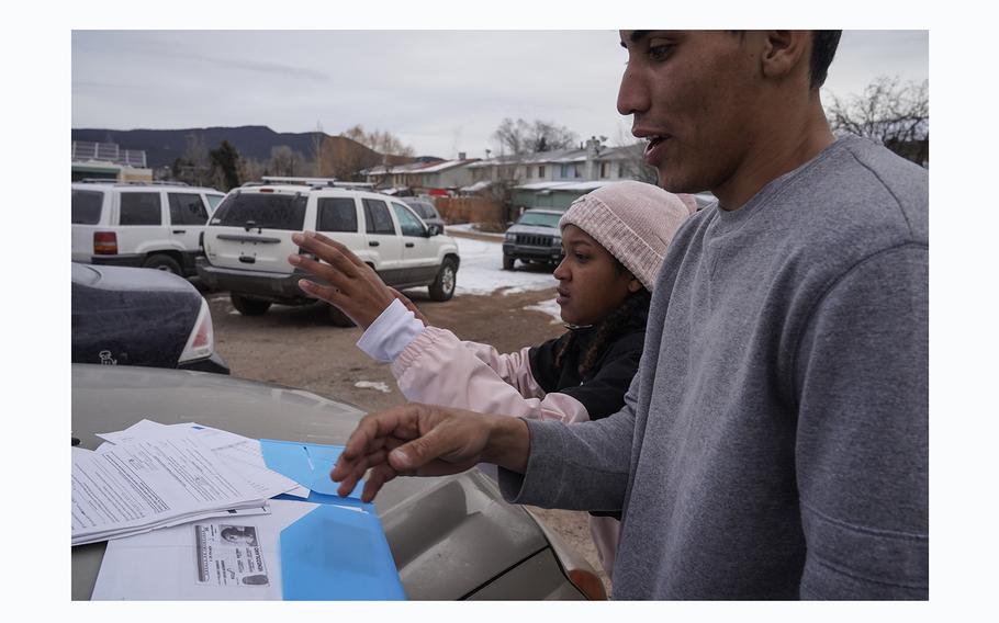 Oscar Flores and Yusbeily Vargas look over legal documents on the hood of their car.