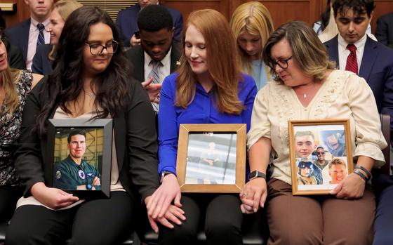 Relatives of service members killed in Osprey aircraft crashes clasp hands before a hearing on the Department of Defense’s V-22 Osprey program, June 12, 2024, on Capitol Hill in Washington.
