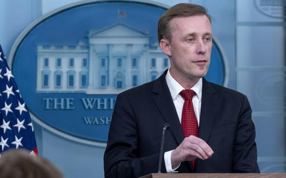 A man in a dark suit speaks into a microphone while standing at a podium in front of the emblem of the White House.