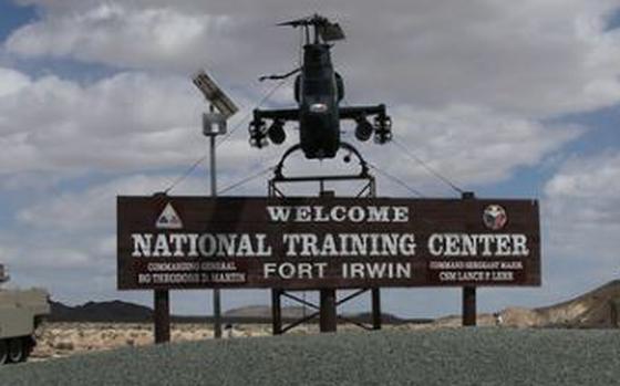 A welcome sign outside the National Training Center at Fort Irwin, Calif., with a helicopter above it.