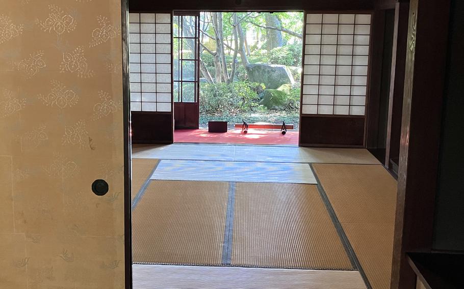 Sliding doors open to reveal a room containing a tatami mat, screens with paper panels and a narrow, enclosed porch.