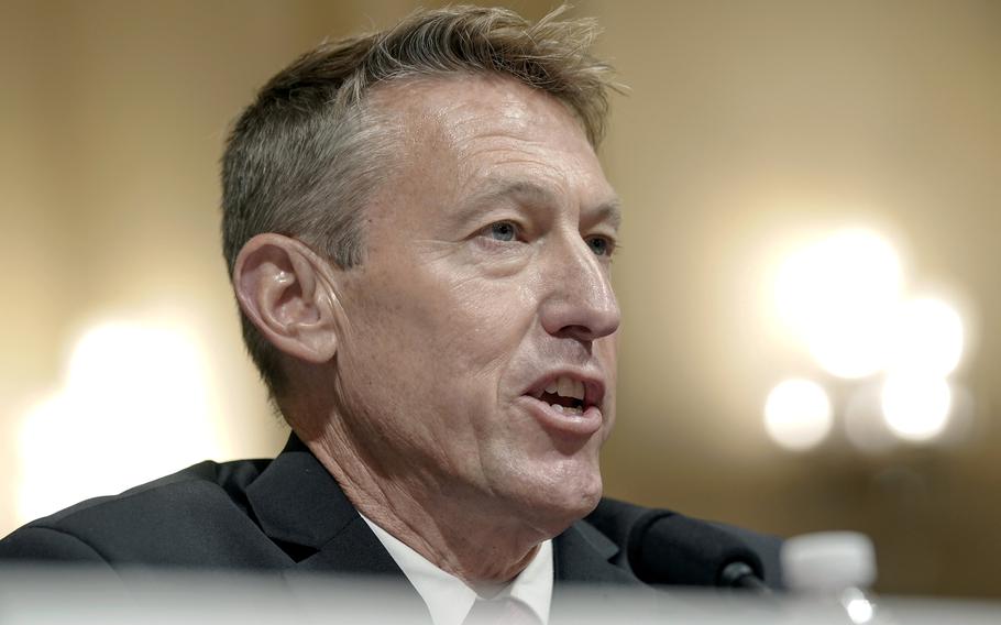 A man in a dark suit sits at a microphone while tesstifying during a congressional hearing.