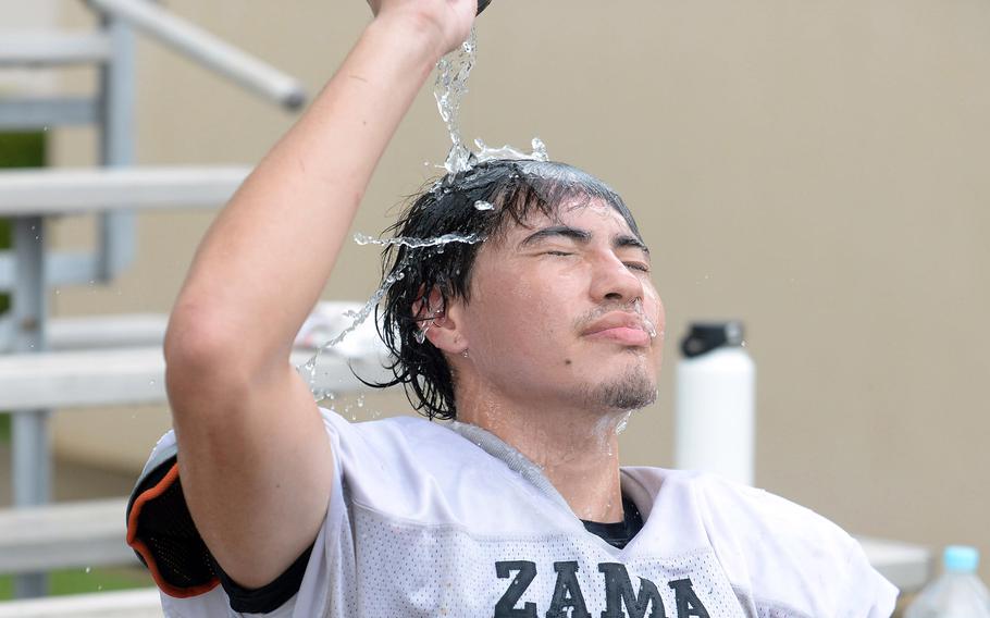 Zama senior lineman Greg Horton cools down during a water break. Intense summer heat has caused black-flag conditions on bases around Japan, forcing teams to begin practice later in the day.