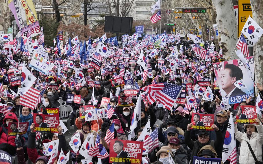 A mass of demonstrators with flags and posters of President Yoon Suk Yeol.