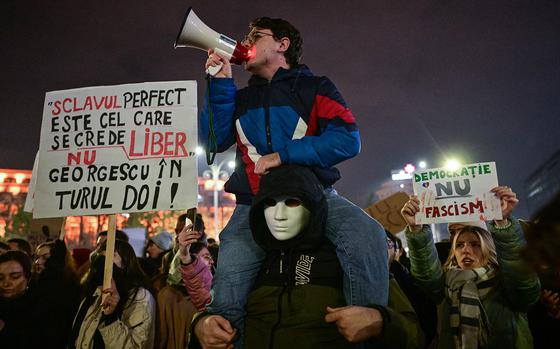 Romanians protest the surprise win of a far-right outsider candidate in the first round of presidential elections, with one sign on the right reading (in Romanian) ““democracy rather than fascism.”