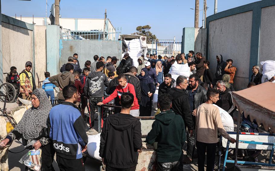 Palestinians wait to receive bags of flour on Jan. 1, 2024, outside U.N. warehouses east of Rafah in the southern Gaza Strip. 