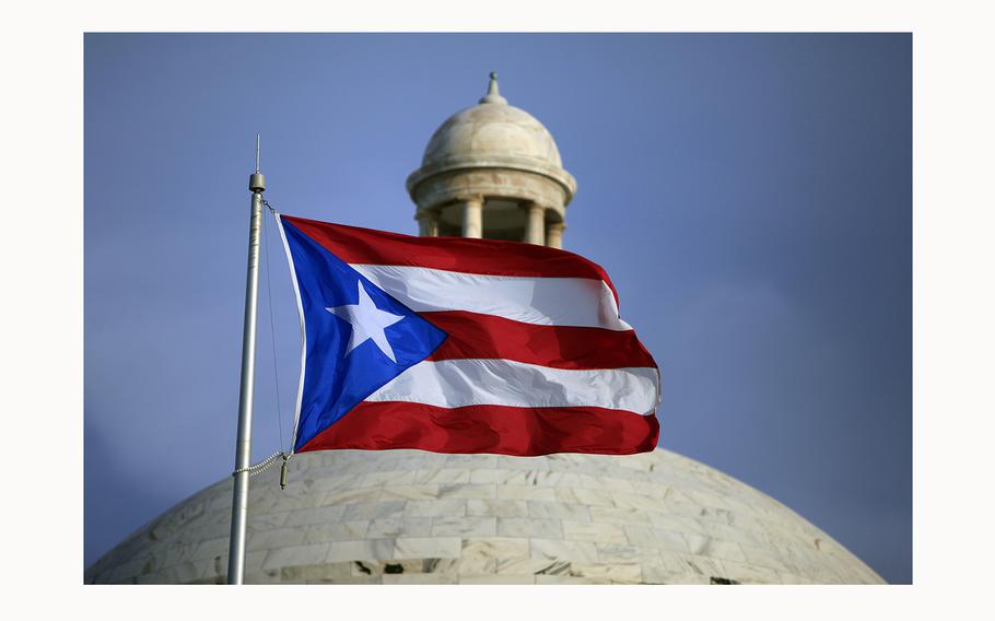 A Puerto Rican national flag flies in front of the Capitol building in San Juan, Puerto Rico, July 29, 2015. Puerto Rico’s Justice Department is suing at least 30 ex-government officials accused of corruption that cost the island more than $30 million in public funds. 