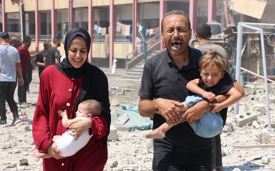 Palestinians carry their children as they flee after an Israeli strike on a school, housing displaced Palestinians, in the Rimal neighbourhood of central Gaza City on Aug. 20, 2024, amid the ongoing conflict between Israel and the militant Hamas group. 