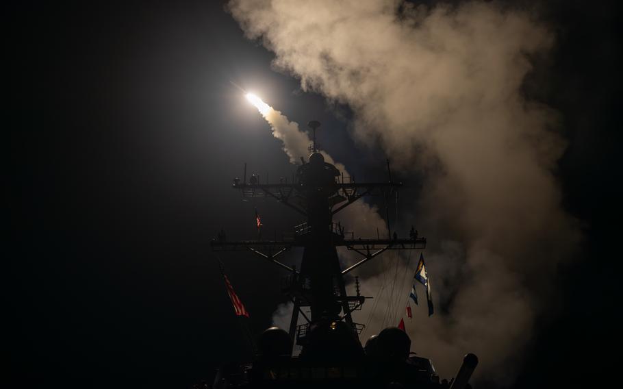 A missile takes flight, and smoke rises from the USS Gravely.