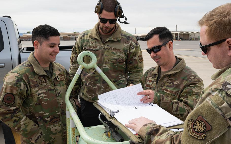 Three airmen gather around and look over sheets of paper