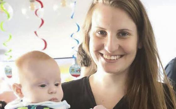 A woman poses while holding a baby boy.