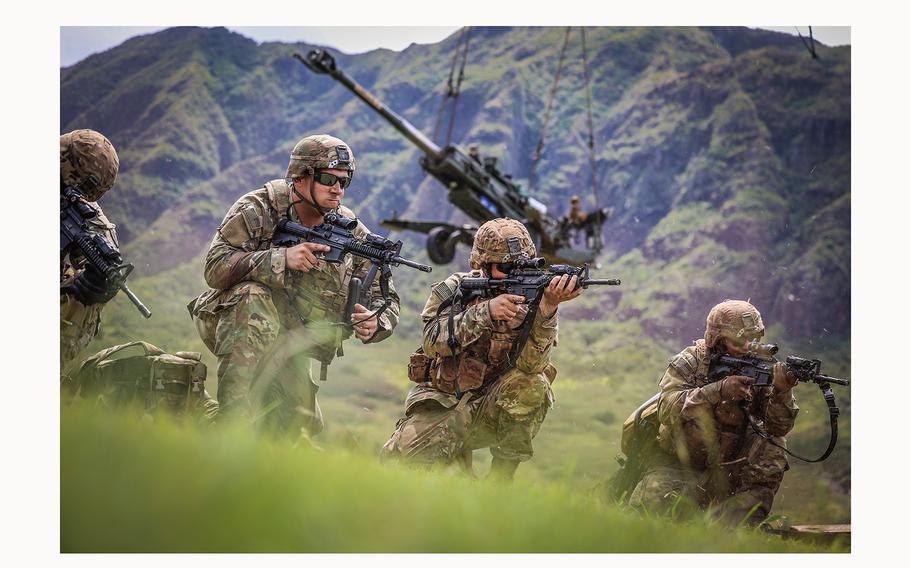 U.S. service members take part in an exercise at Hawaii’s Makua Valley in September 2021. In the background is an M777A2 howitzers being sling loaded onto a helicopter.