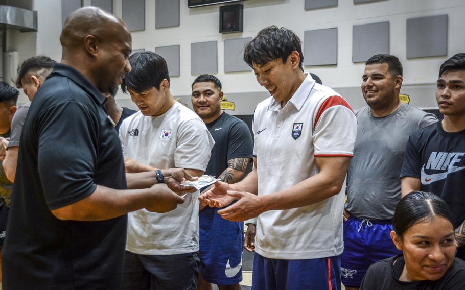 Seo Bum Gue, a South Korean national team wrestler, receives a challenge coin from Dion Jordan, chief of sports, fitness and aquatics, during a wrestling seminar in Carey Fitness Center at Camp Casey, South Korea, June 18, 2024. 