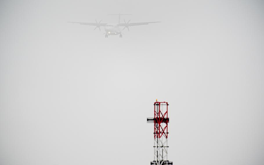 A plane is barely visible as it lands in thick fog.