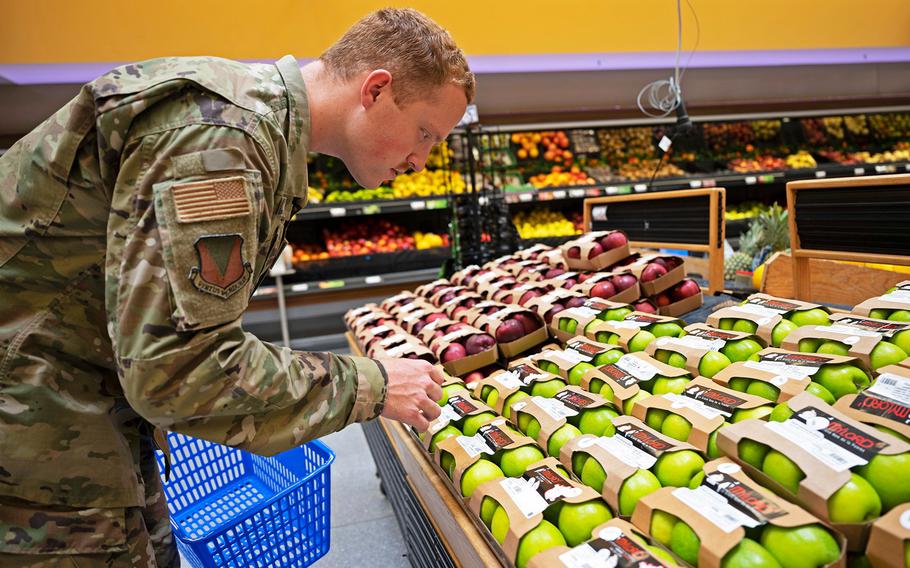 A photo of an American airman selecting produce while grocery shopping at Ramstein Air Base, Germany, May 17, 2022.