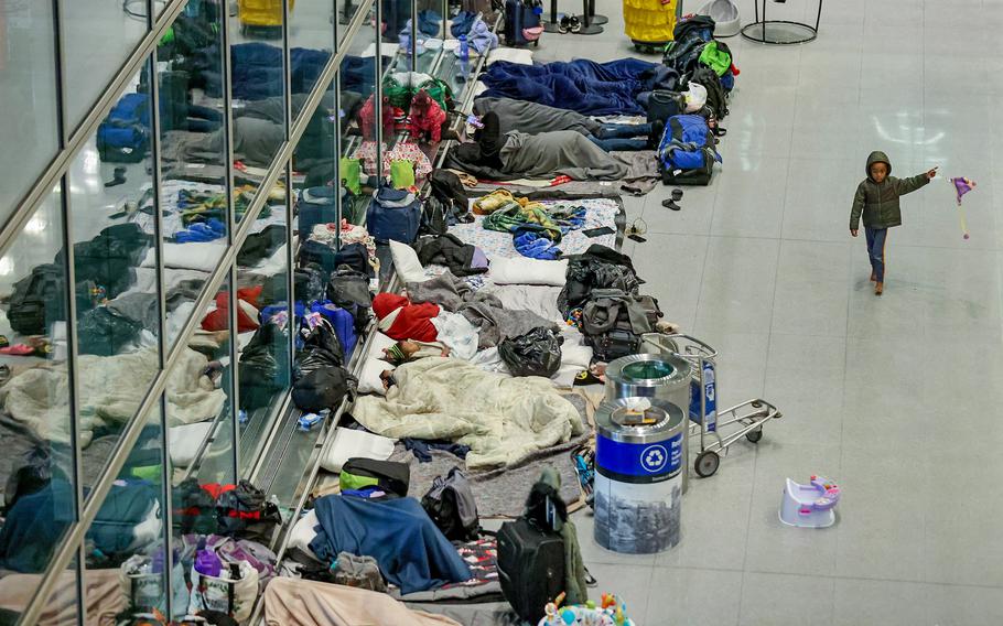 Migrants spend the night on the floor in January at Logan Airport in Boston. Spending on the Massachusetts emergency shelter system topped $700 million as of June, according to a new report. 