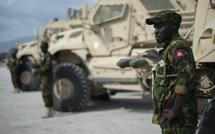 A Kenyan member stands next to an armored vehicle