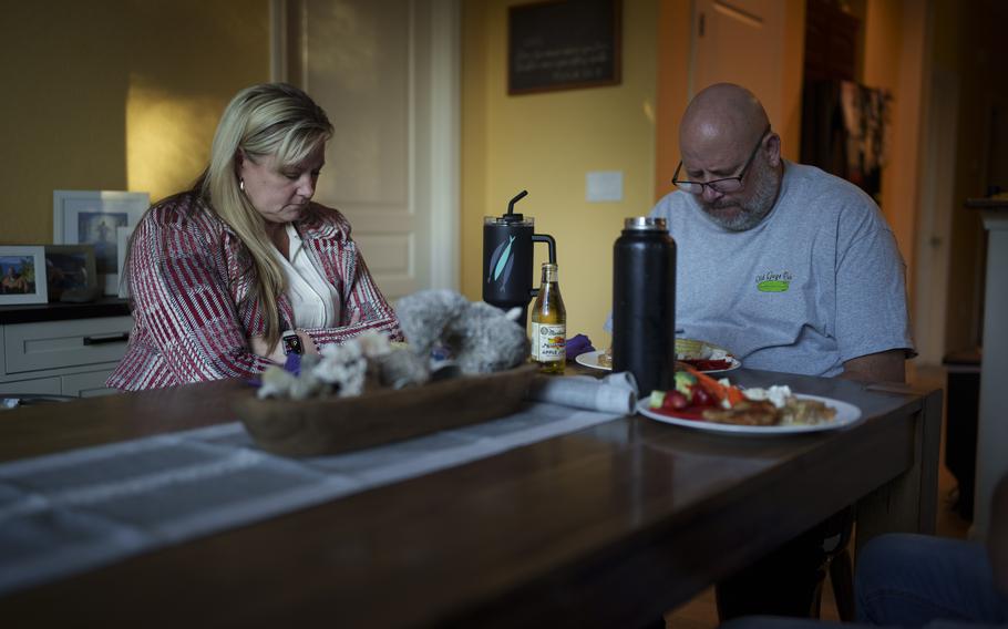 Cari-Ann Burgess, interim Registrar of Voters for Washoe County, Nev., left, prays with her husband Shane Burgess before eating dinner at their home Friday, Sept. 20, 2024, in Reno, Nev.