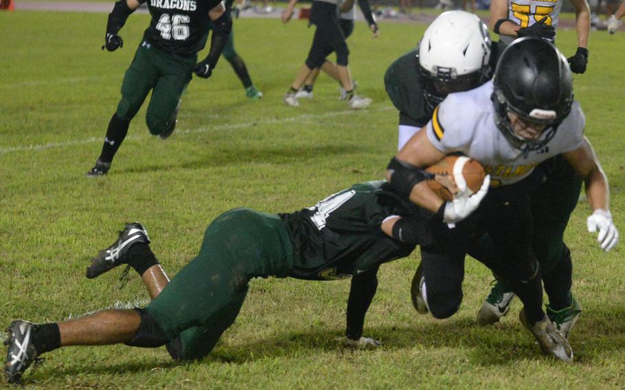 Kubasaki's Josiah Good and Tai McMillan bottle up ASIJ running back Micah Eickbush.