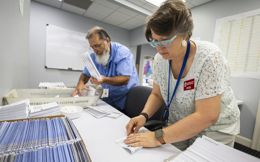 A man and a woman fold ballots for mailing.